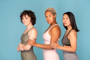 Side view of young mixed-race sportswoman standing between her two friends