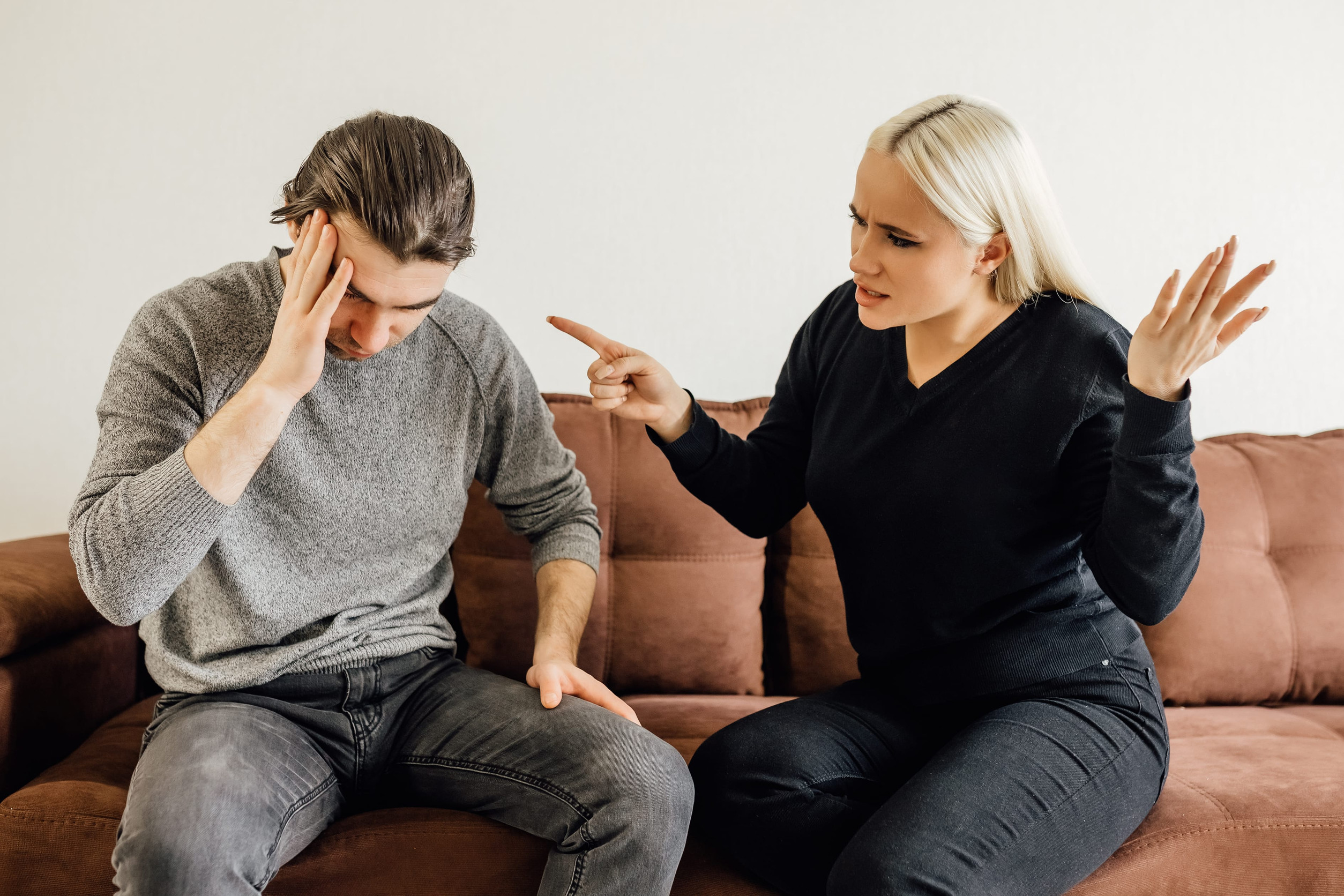 Aggressive caucasian wife Shouting At Unhappy Victimized Husband Sitting On Couch At Home. Family Conflicts, Quarrels And Domestic Violence, Marriage And Relationship Crisis Concept. Selective Focus
