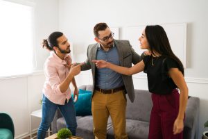 Caucasian psychologist standing between a husband and wife fighting while talking about their problems during therapy