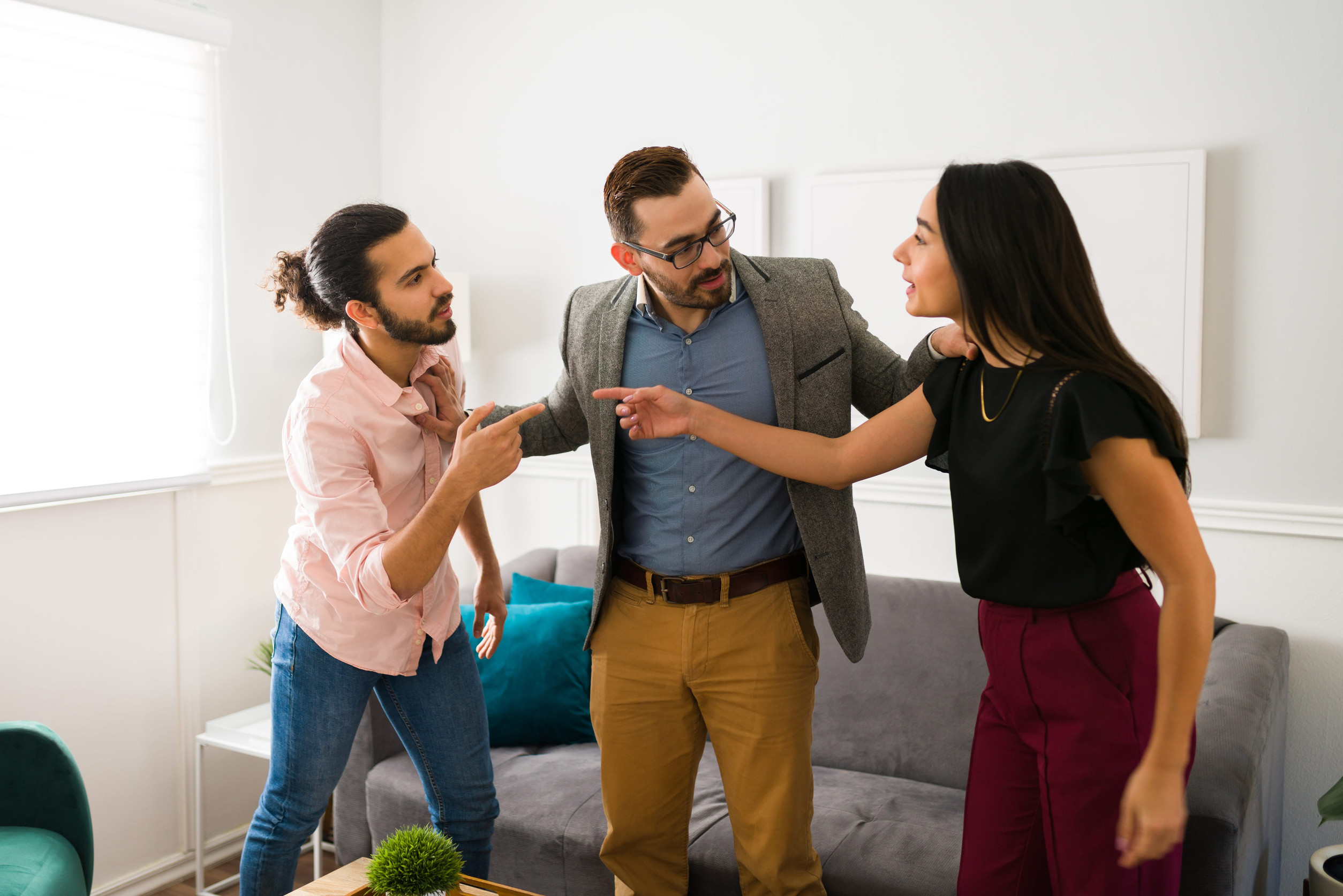 Caucasian psychologist standing between a husband and wife fighting while talking about their problems during therapy