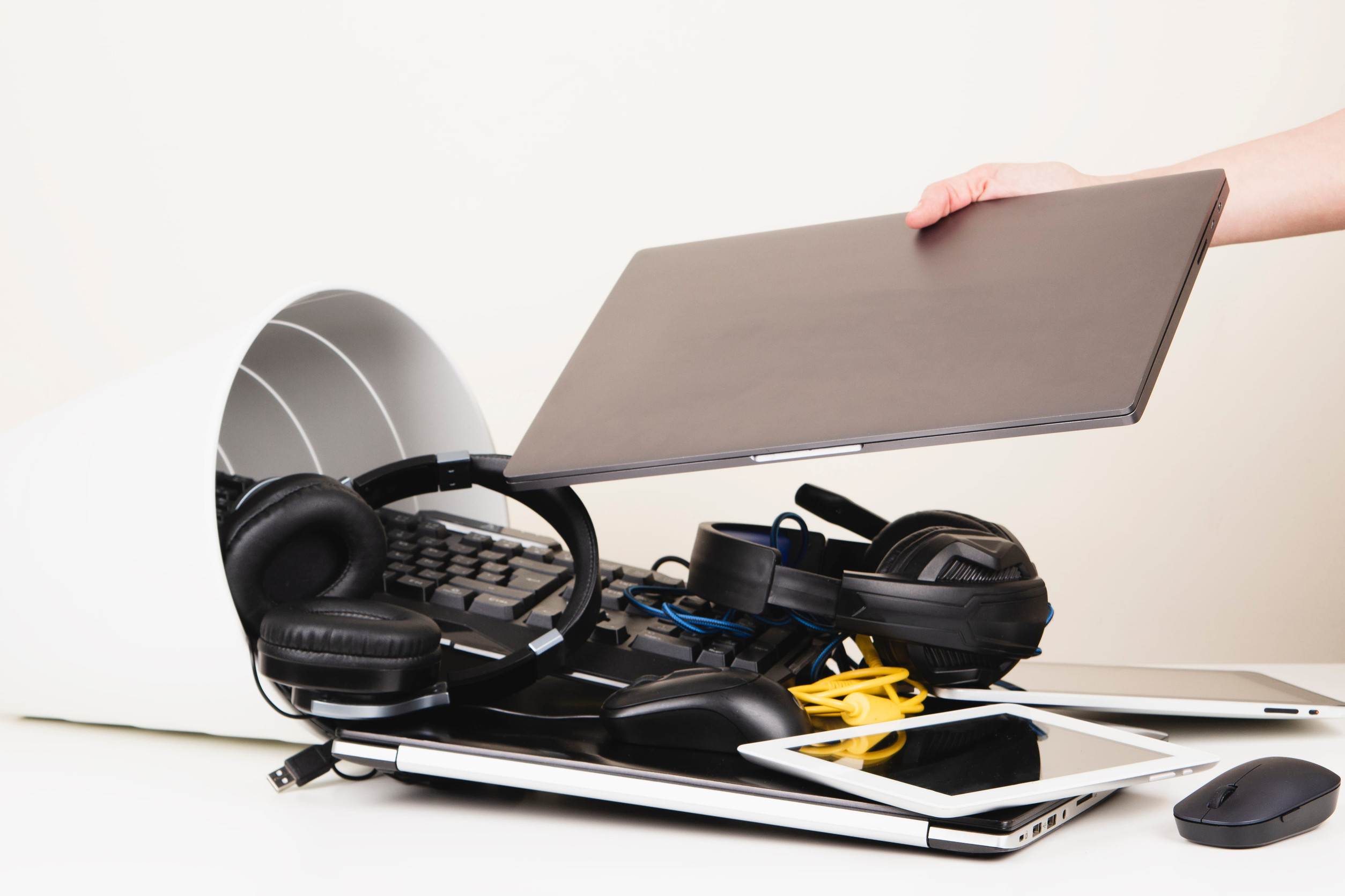 Woman hand put used laptop to recycling bin full of old computers, phones, tablets, cords and electronic devices. Planned obsolescence, e-waste, electronics waste for reuse and recycle concept
