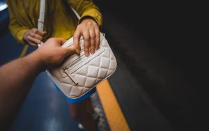 Thief steals a bag from a woman in the subway.