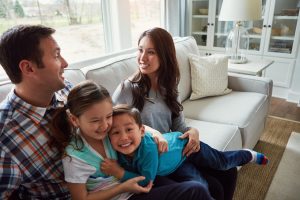 Family, that forever kind of love. a happy young family of four bonding together on the sofa at home.