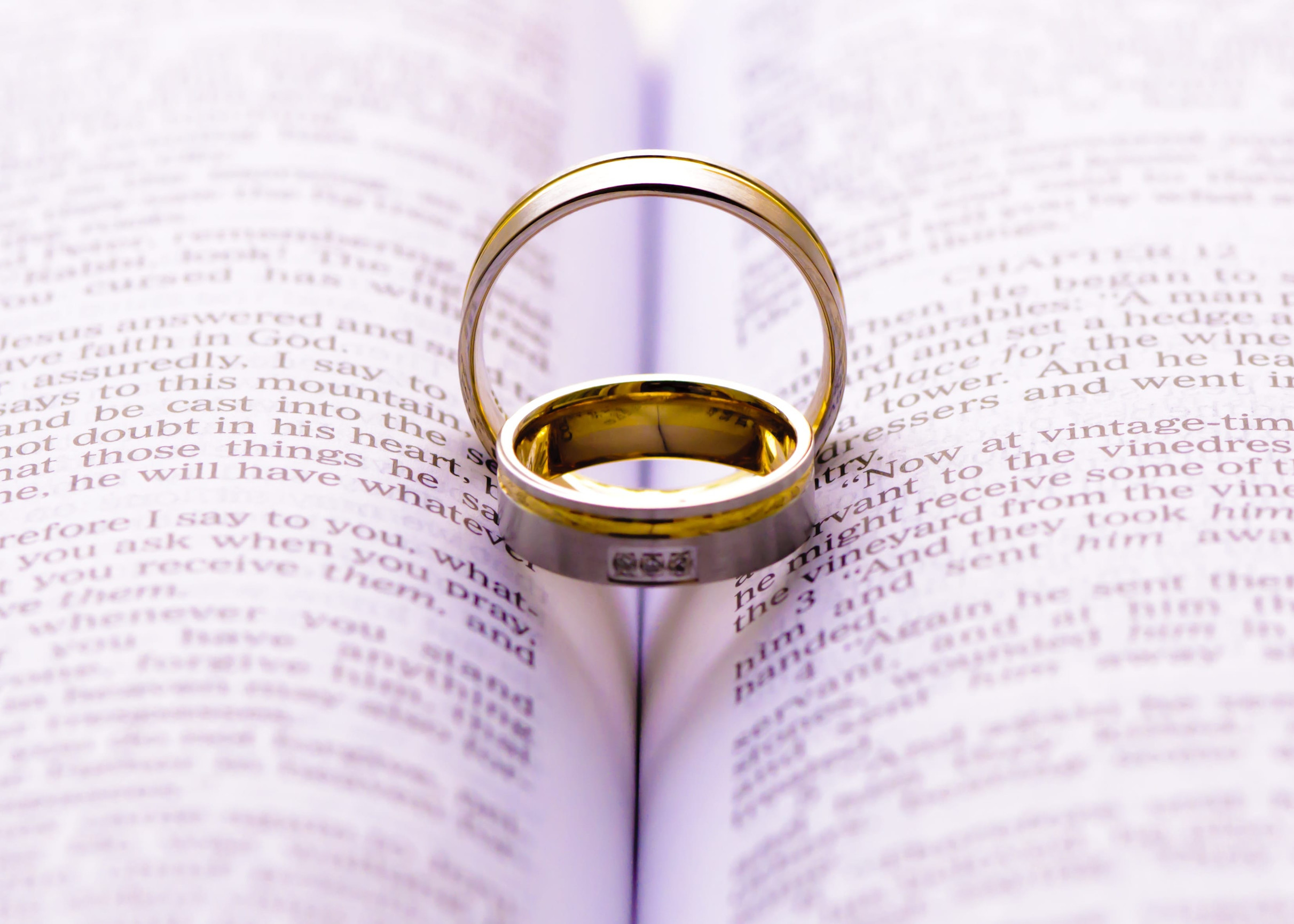 Wedding rings on a Bible with shadow shape heart