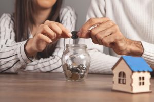 a man and a woman throw coins into a piggy bank at home