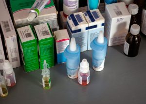 Boxes and bottles with medicines. On the table are eye drops, tinctures, ointments and medicines in boxes. View from above. Medical background for industry, science, pharmacies, clinics.