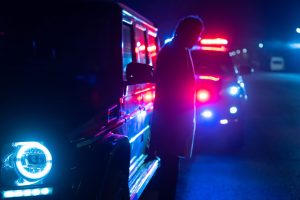 police officer stands next to a car he pulled over for speeding, reaching for the driver's ID, stock photo