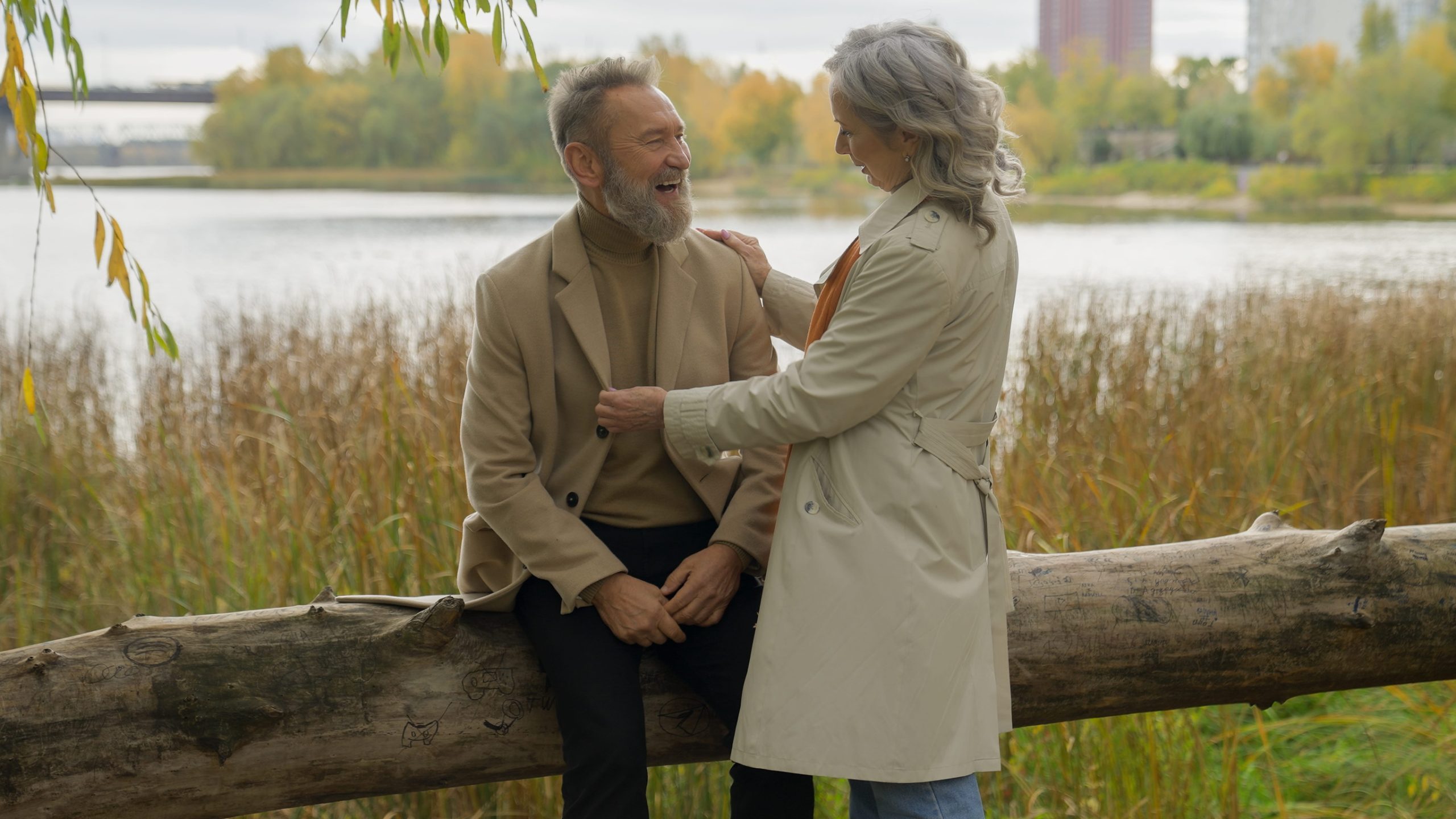 Happy family Caucasian mid age couple female male rest together autumn weekend senior man talking to mature woman two grandparents laughing having fun at park near lake romantic date in city outdoors