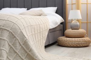 Side table with lamp near bed indoors