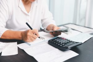 Using calculating machine, household carefully manages each bill and expense to plan financial budget, ensuring timely payment, consistent saving, smart investment for secure home finance strategy.