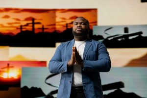 Spiritual man meditates on faith and holiness in a pose of worship and surrender, praise the Lord. The background of crosses symbolizes religion and the higher power of devotion.