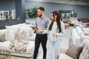 Young woman discussing furniture options with a male sales consultant in a modern showroom, buying new home furnishings