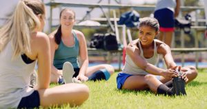 Stretching, group and women on sports field, practice and preparing for workout routine and outdoor. Training, team and people with determination for competition, wellness and warm up for exercise