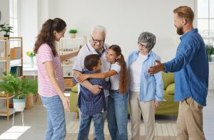 Granddad, granny, we missed you. Multigenerational family having good time together. Grandchildren are happy to meet grandparents. Joyful mom, dad, grandma, grandma and children hugging in living room