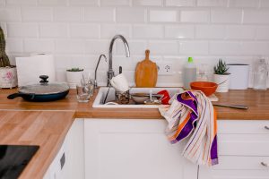 Clutter, dirty dishes by the sink in the white kitchen.