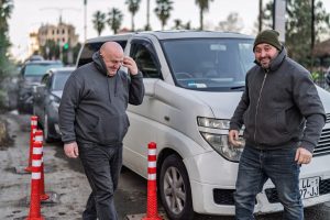 Batumi, georgia 21 april 2026: two georgian men smiling and talking on a city street, standing near a white van and traffic cones, feeling good outside