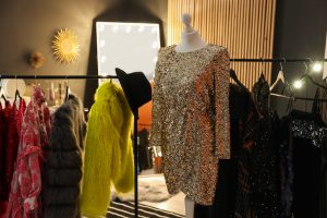 Mannequin with beautiful dress, other festive clothes and mirror in dressing room