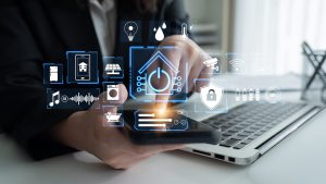 Hands Using Smartphone with Smart Home Icons Representing Technology, Automation, and Connectivity in a Modern Workspace Setting Quark.
