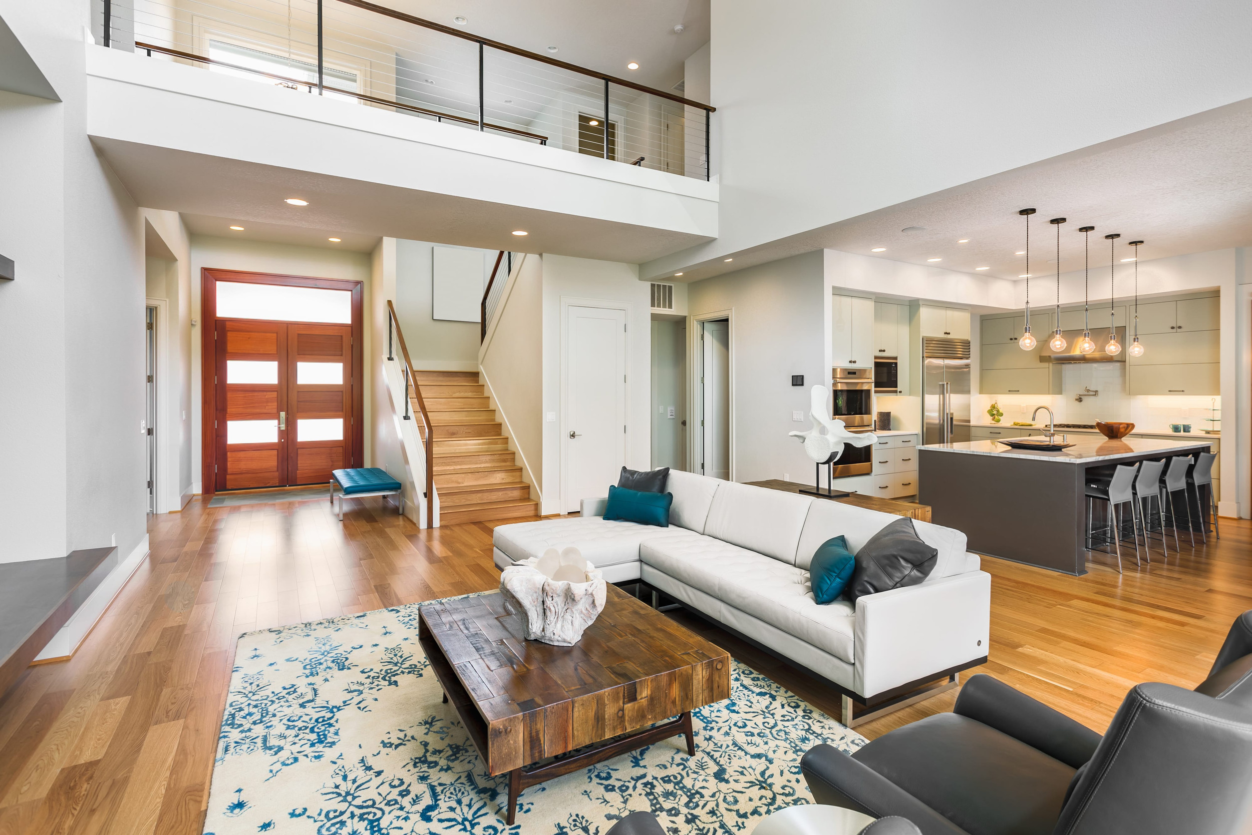 living room in luxury home with view of kitchen, entryfoyer, front door, stairs, and loft area