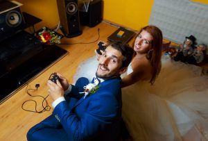 bride and groom playing together videogames with joysticks - gaming and wedding concept