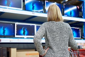 Woman looks at LCD TVs in supermarket