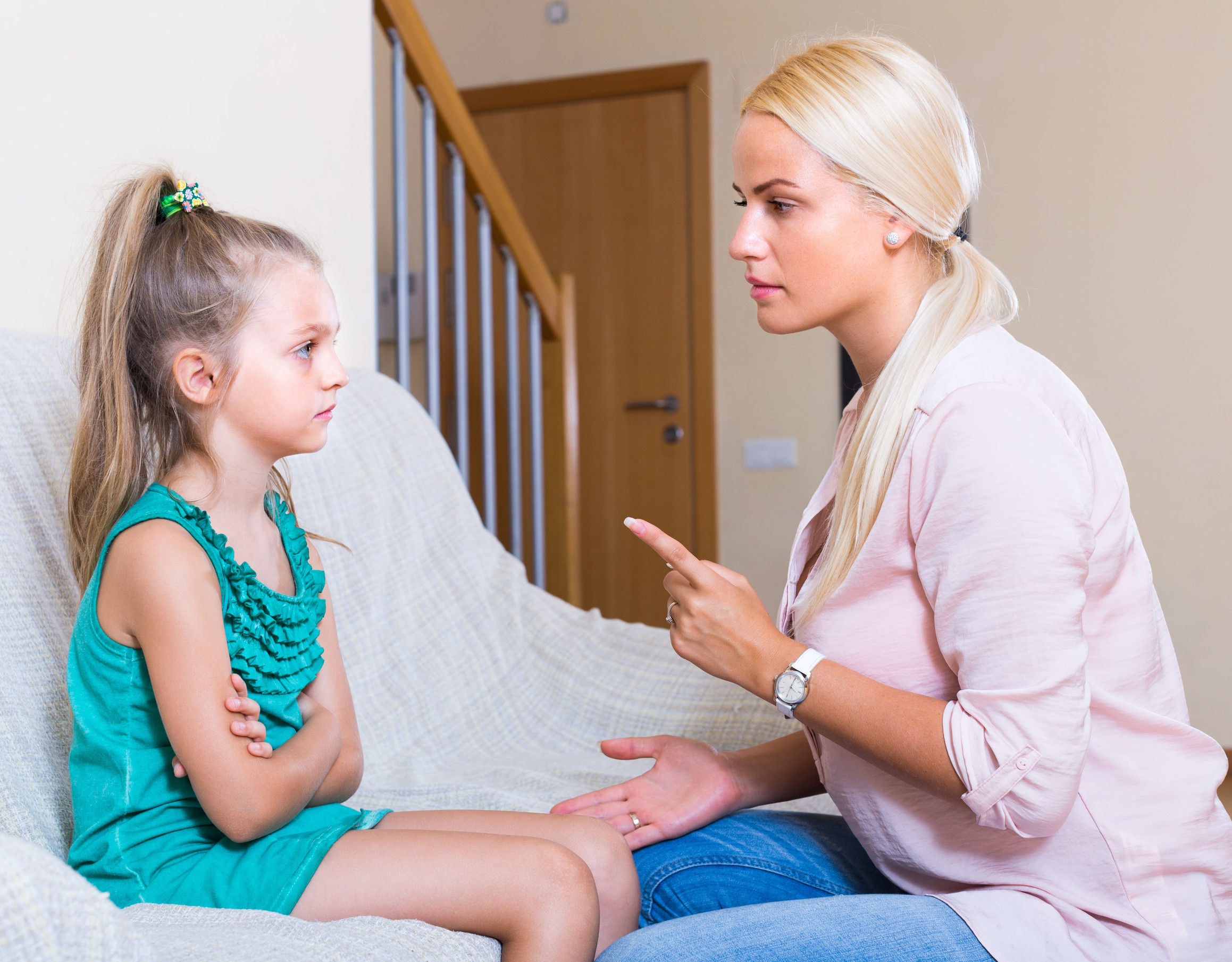 Strict mother scolding mischievous little girl at home