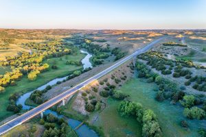 aerial view of a highway and bridge over the Dismal River in Nebraska Sand Hills near Thedford, spring scenery lit by sunrise light