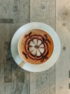 A beautifully crafted cappuccino with intricate latte art on a rustic wooden table in Jammu.