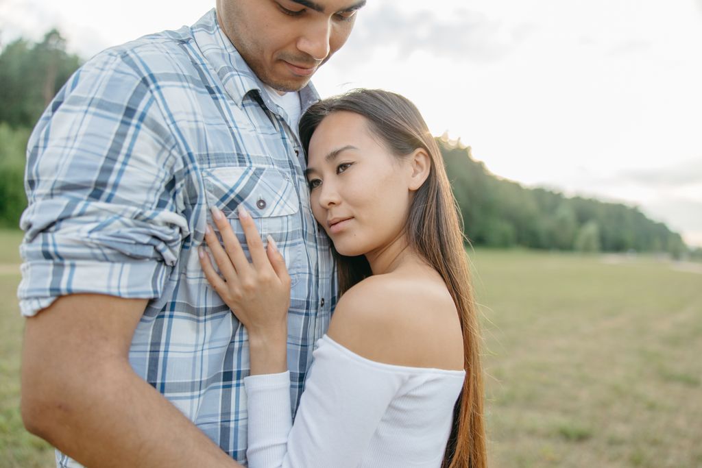 A couple embracing in a sunny park, capturing a tender moment of affection and tranquility.