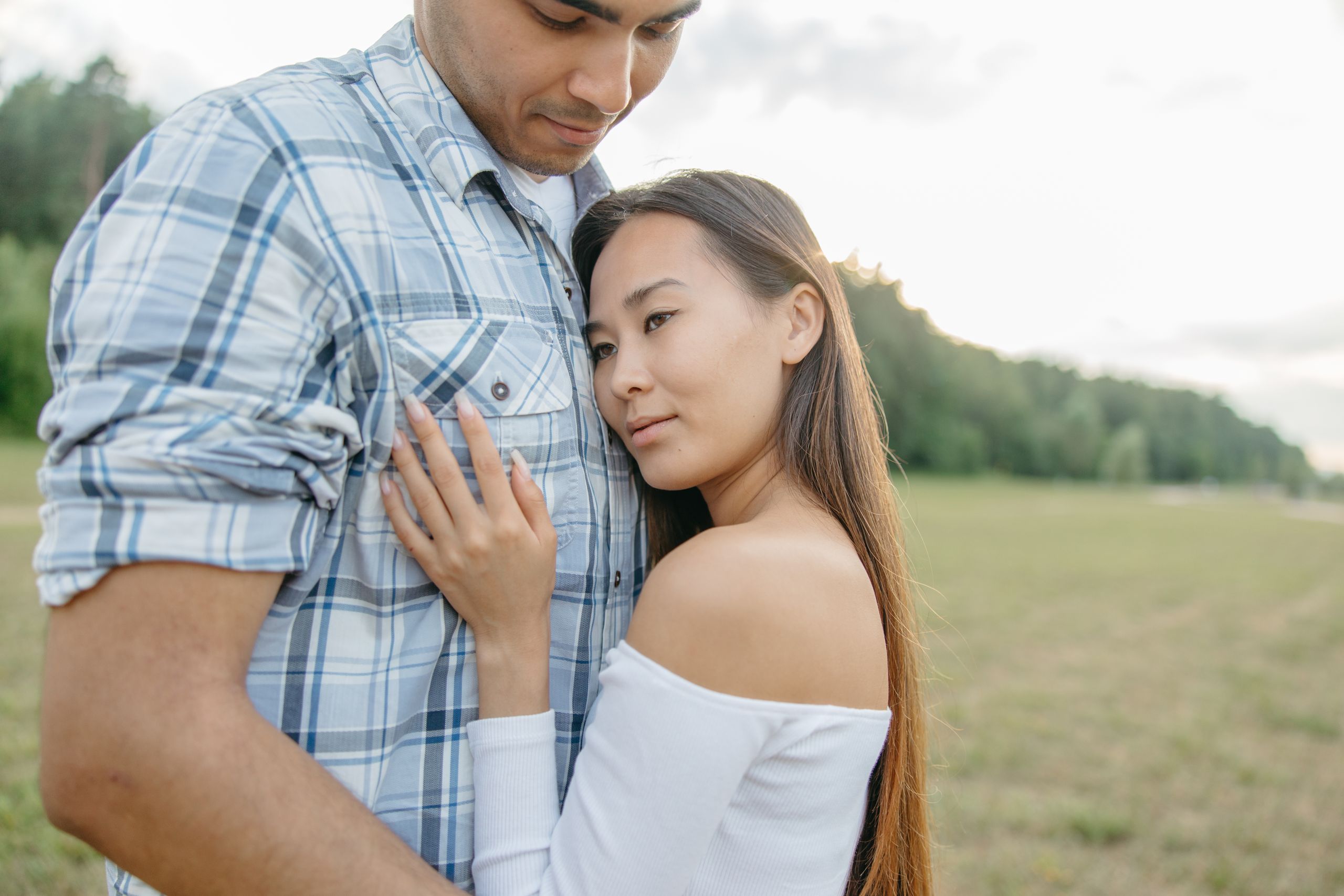 A couple embracing in a sunny park, capturing a tender moment of affection and tranquility.