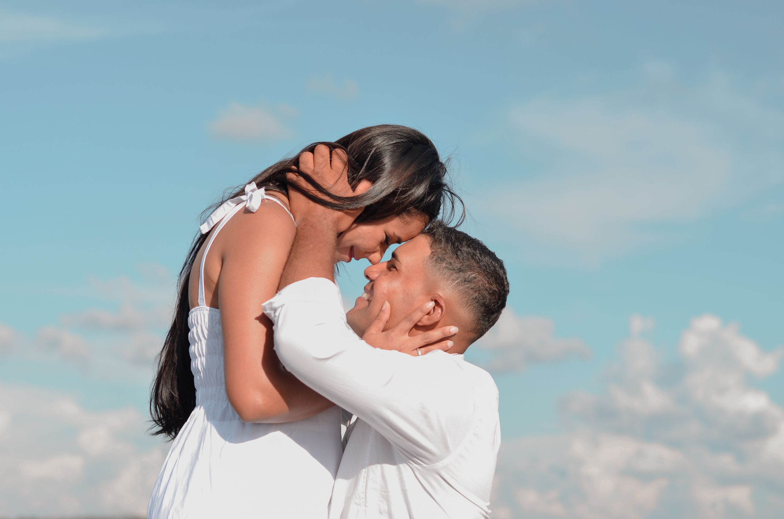 A couple in love embracing under a clear blue sky, exuding romance and warmth.