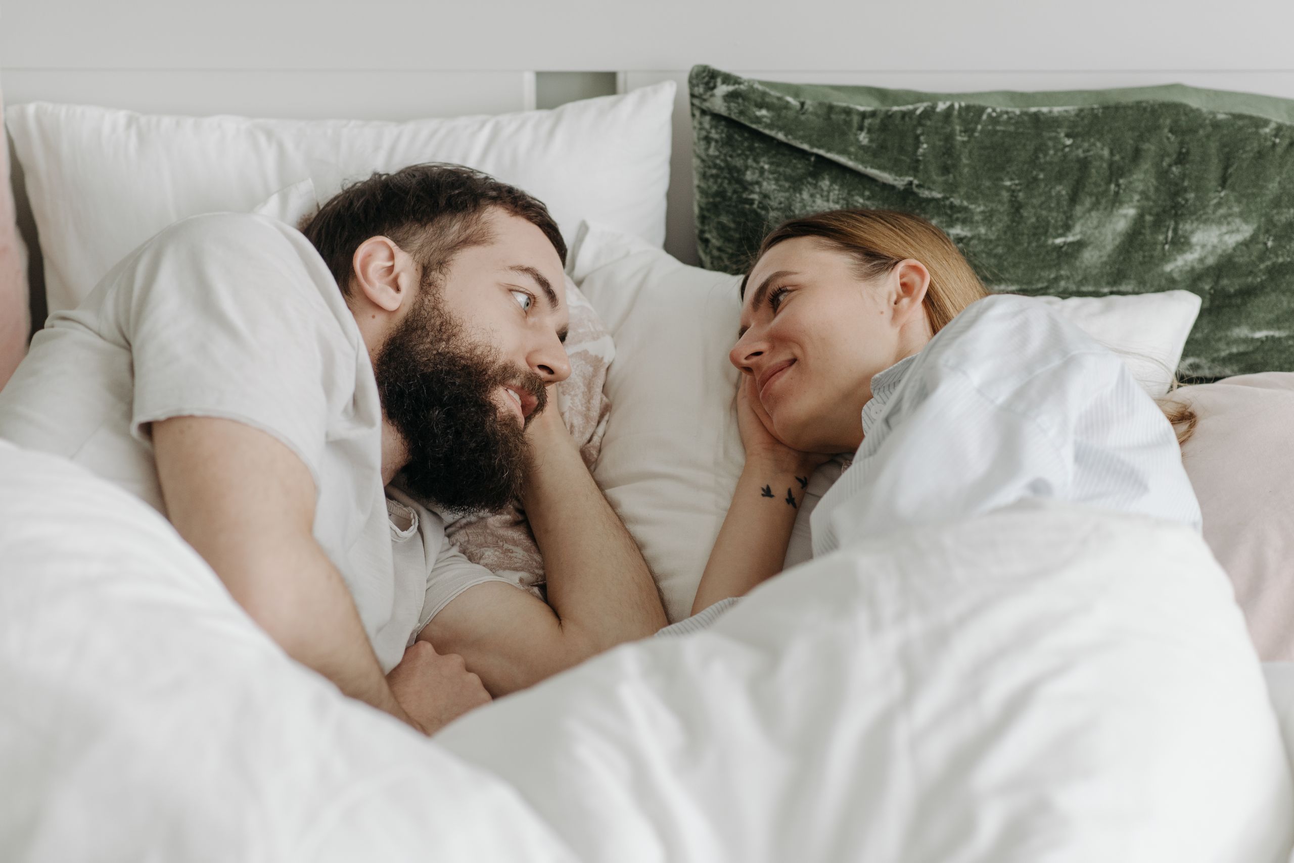 A couple lying in bed sharing a tender moment, conveying love and intimacy.