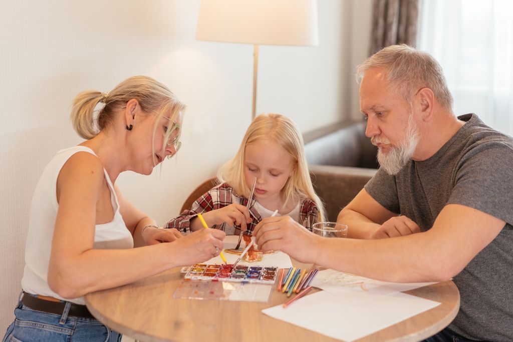 A family of three enjoying creative time with painting and drawing at home.