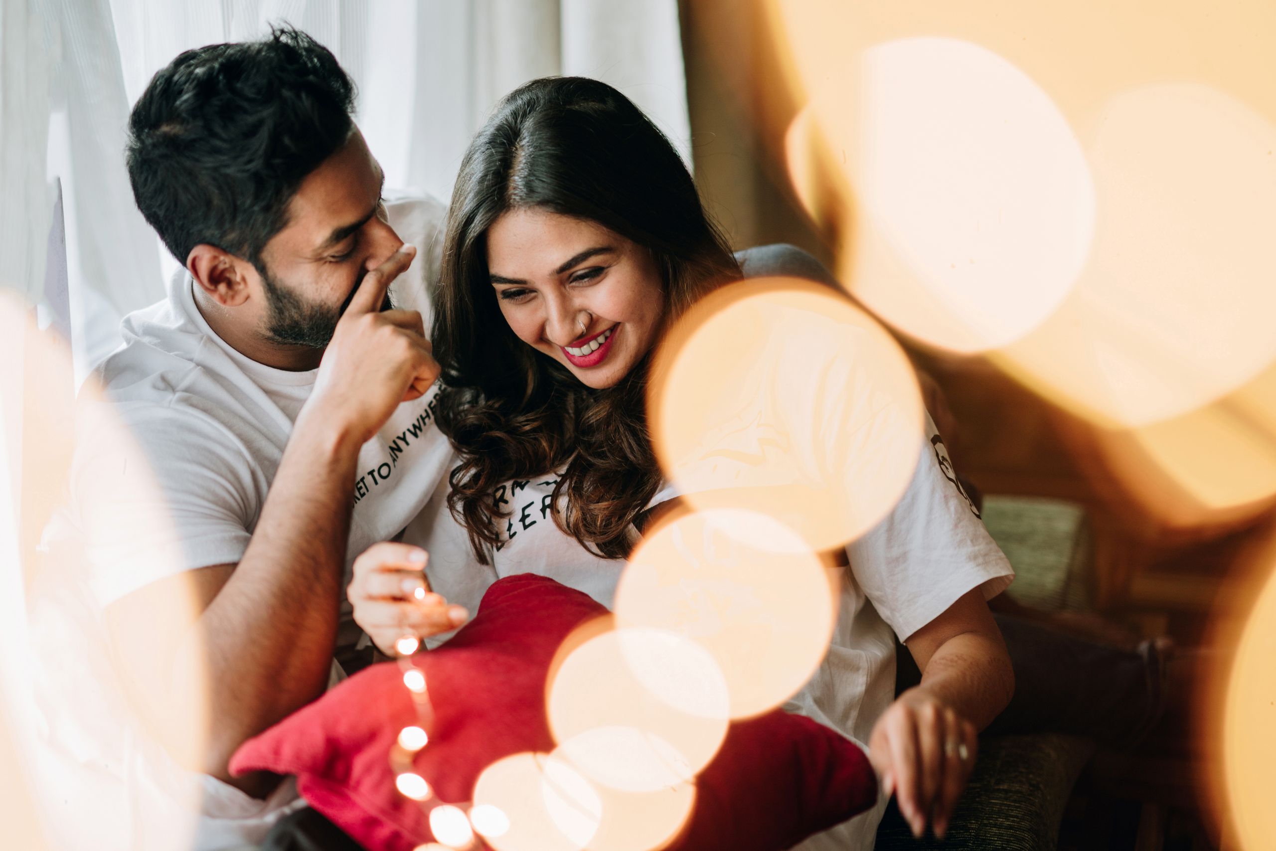 A happy young couple enjoying a relaxed moment together indoors with warm lighting and bokeh effect.
