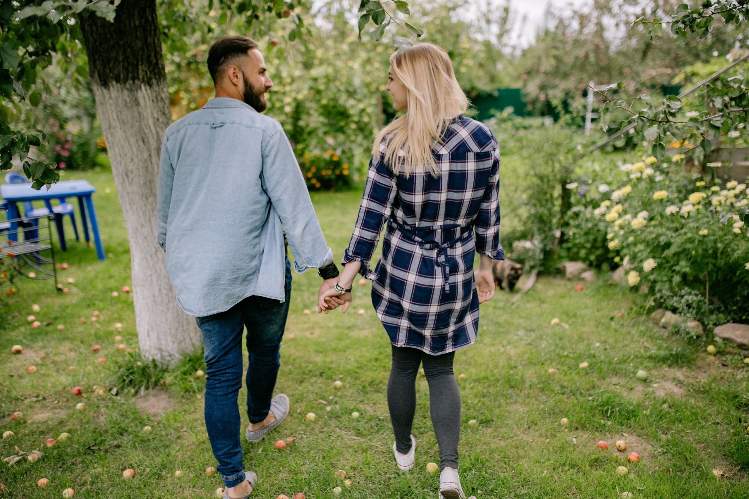 A loving couple holding hands and walking in a lush garden.