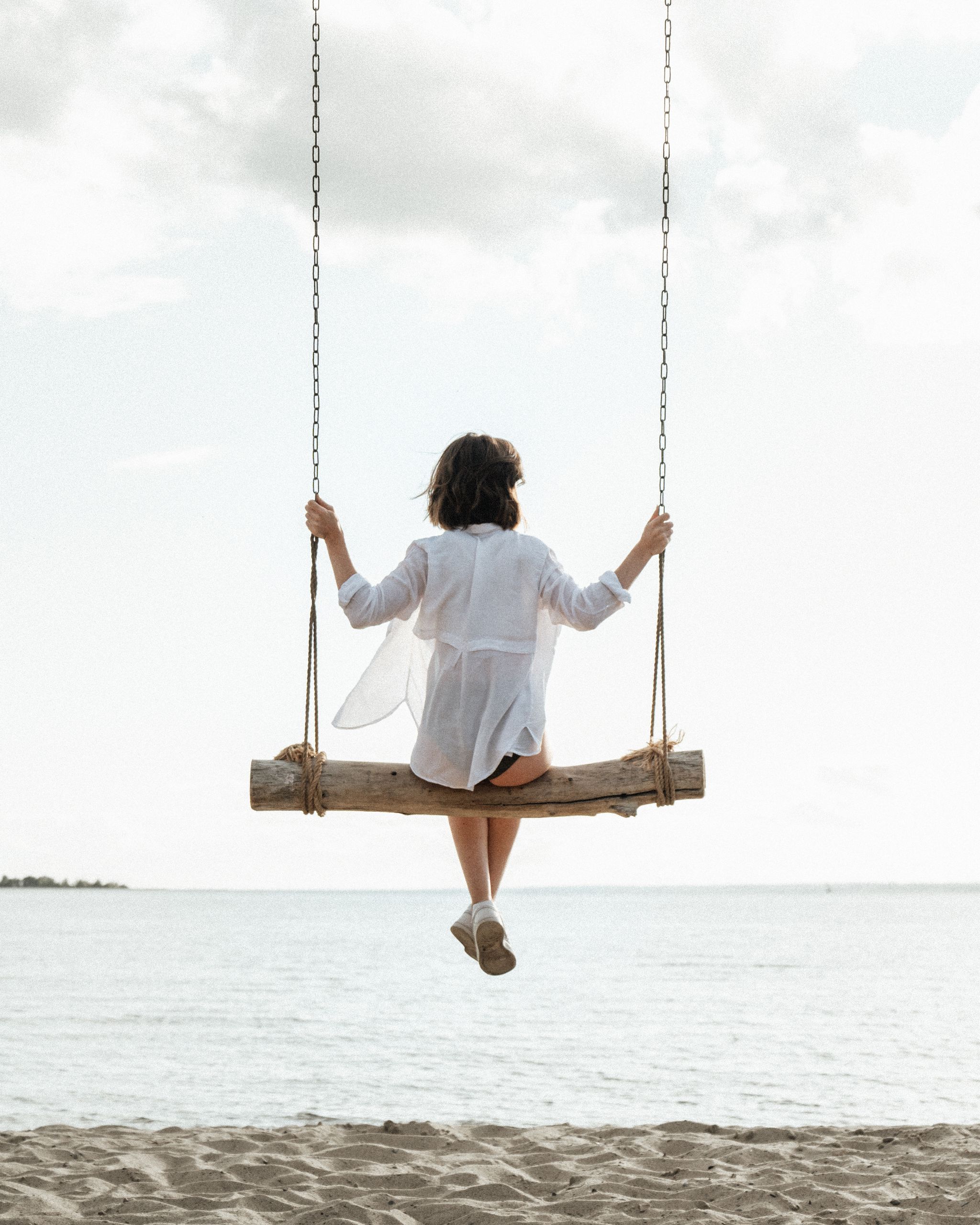 A person enjoys a calming swing by the shoreline, embracing tranquility.