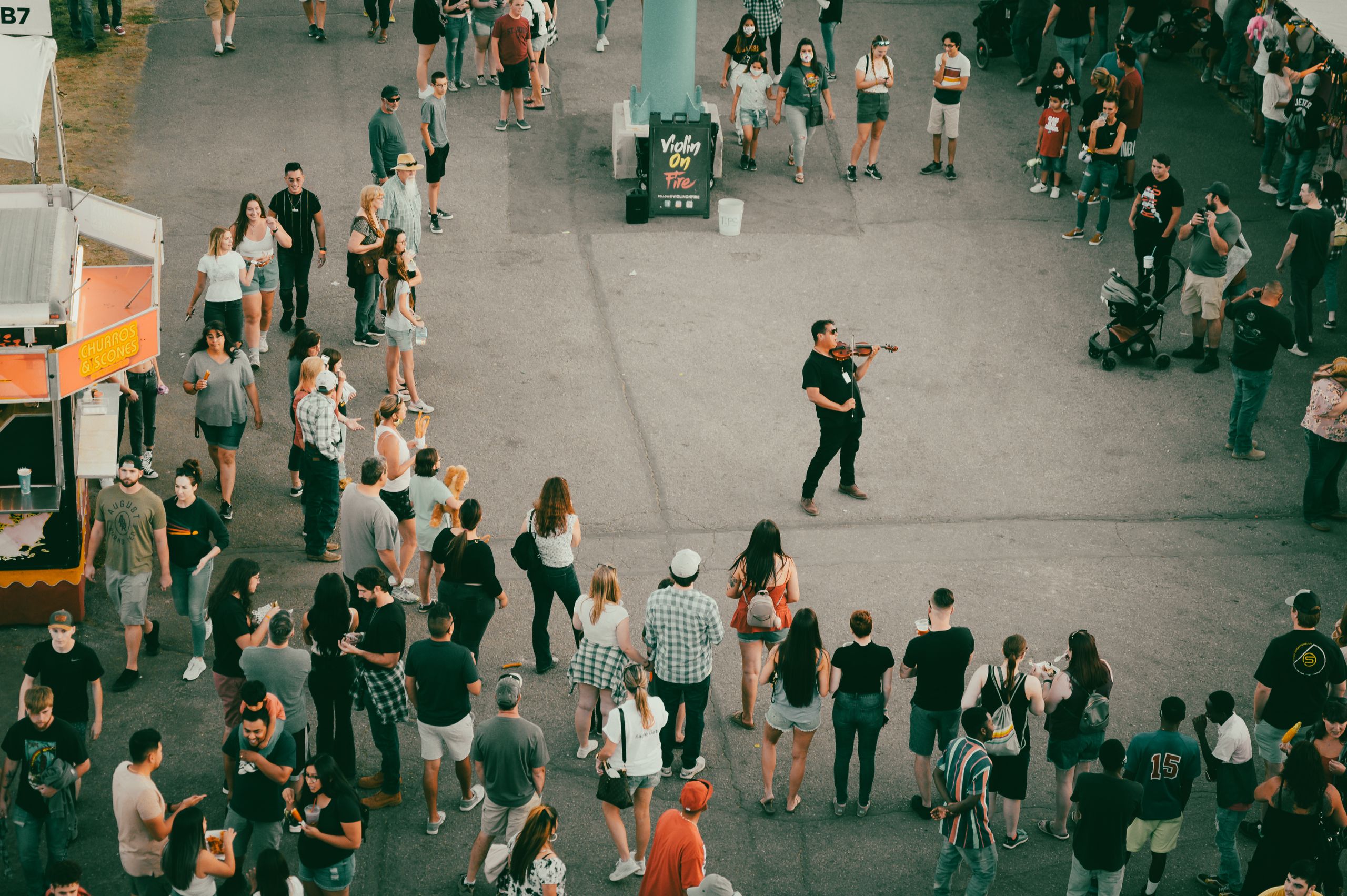 A street performer plays violin amidst a crowd at a Boise festival, capturing the lively atmosphere.