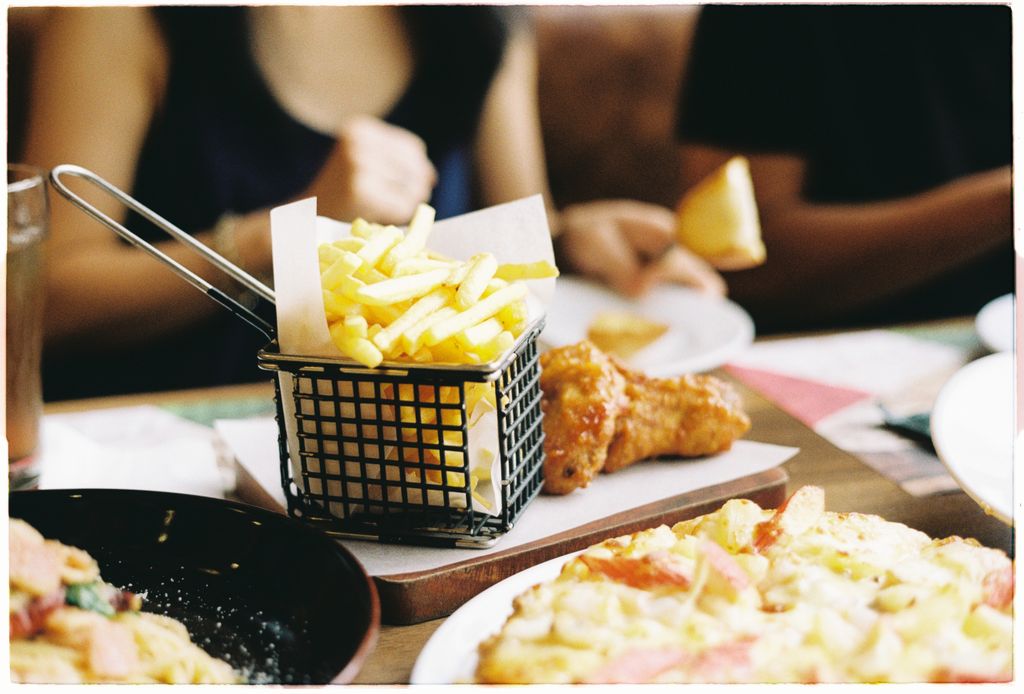 A table setting with fries, pizza, and friends enjoying a casual meal.