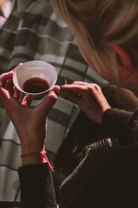 A woman holds a cup of hot beverage, captured from a high angle for a cozy and inviting feel.