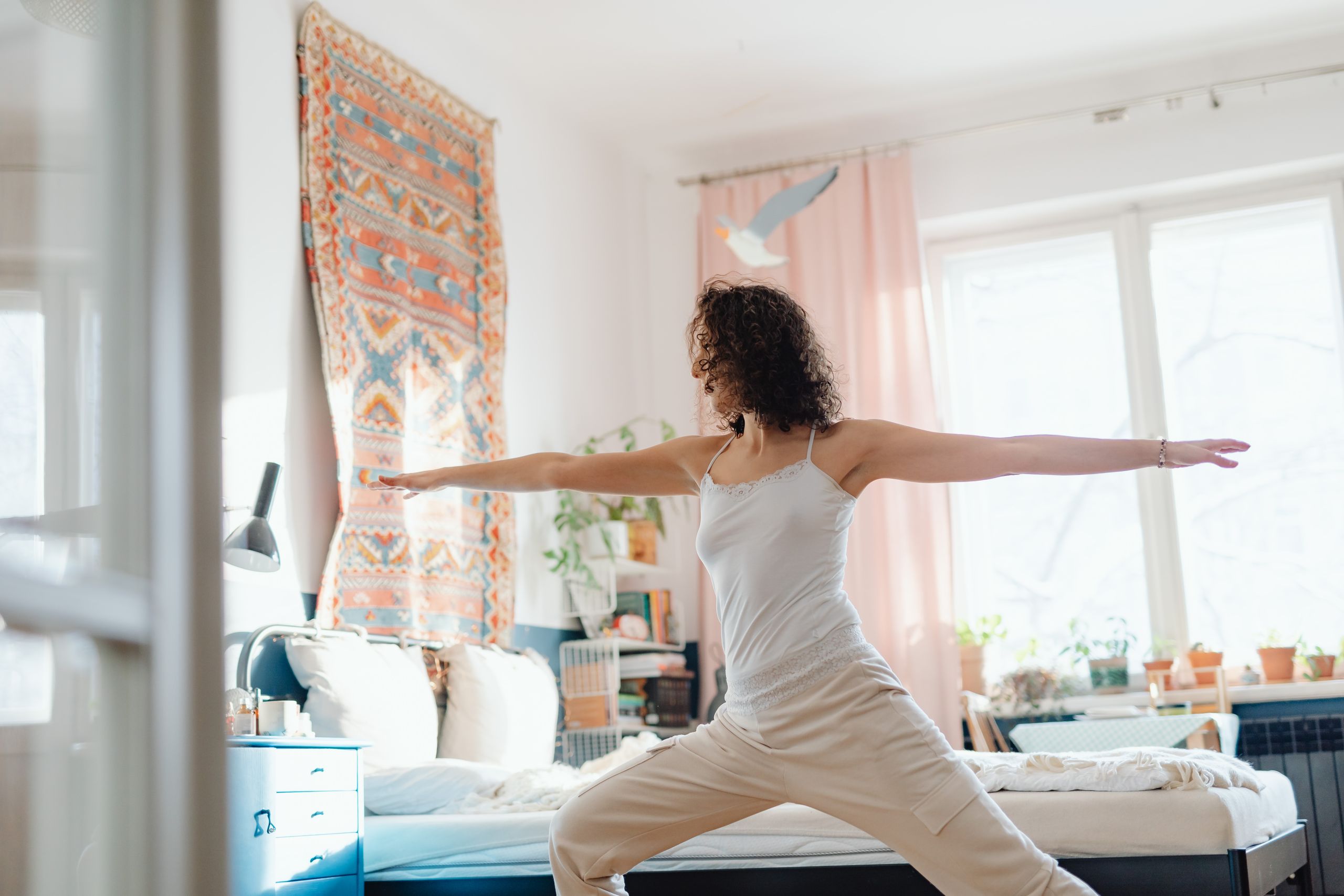 A woman practicing yoga in a bright and cozy bedroom, creating a serene and peaceful atmosphere.