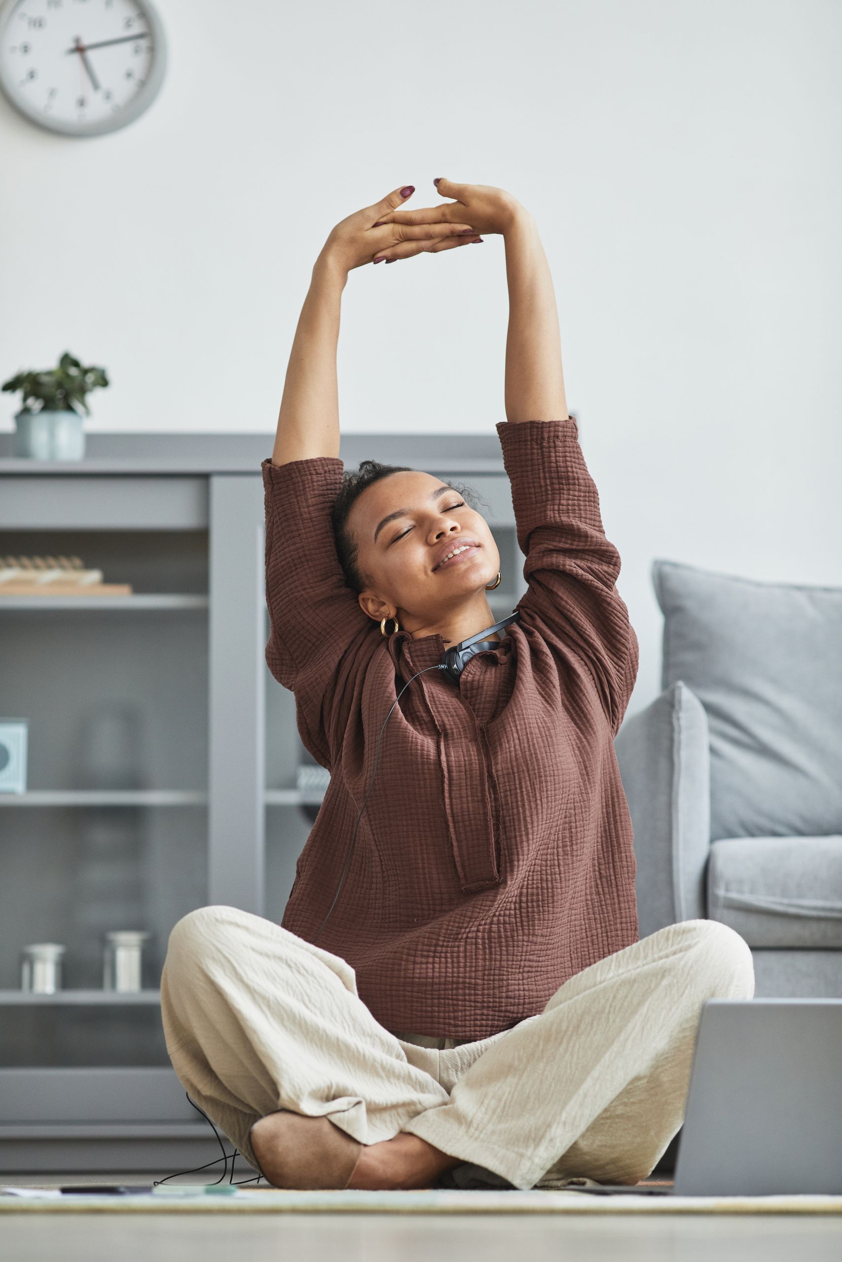 African American woman stretching in a cozy living room, enjoying a moment of relaxation.