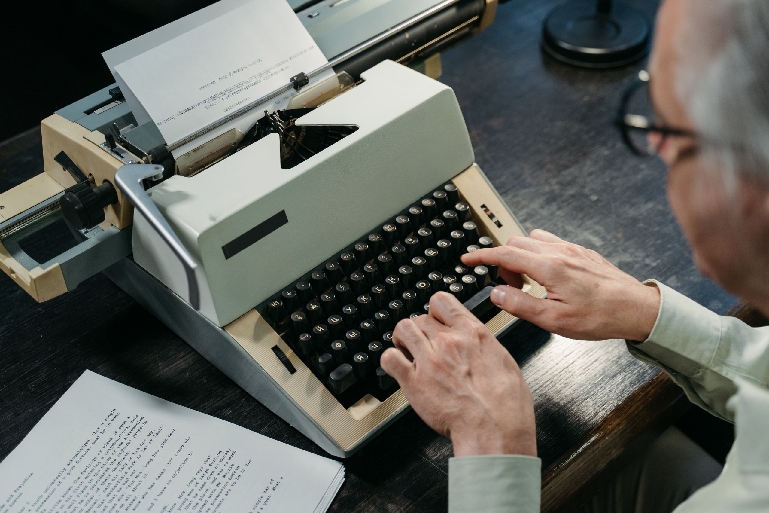 An elderly person types on a vintage typewriter, capturing nostalgia and mechanical artistry.