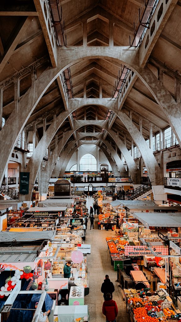An indoor market bustling with activity under the vast arches of Breslau's historic hall.