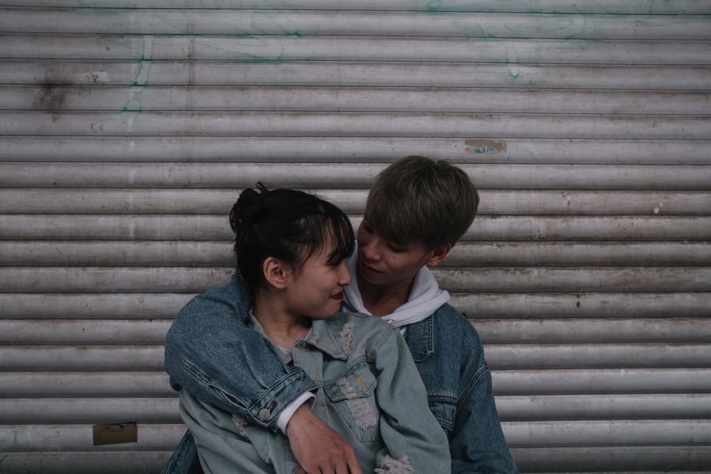 An intimate moment of a young Asian couple in love against an urban backdrop.
