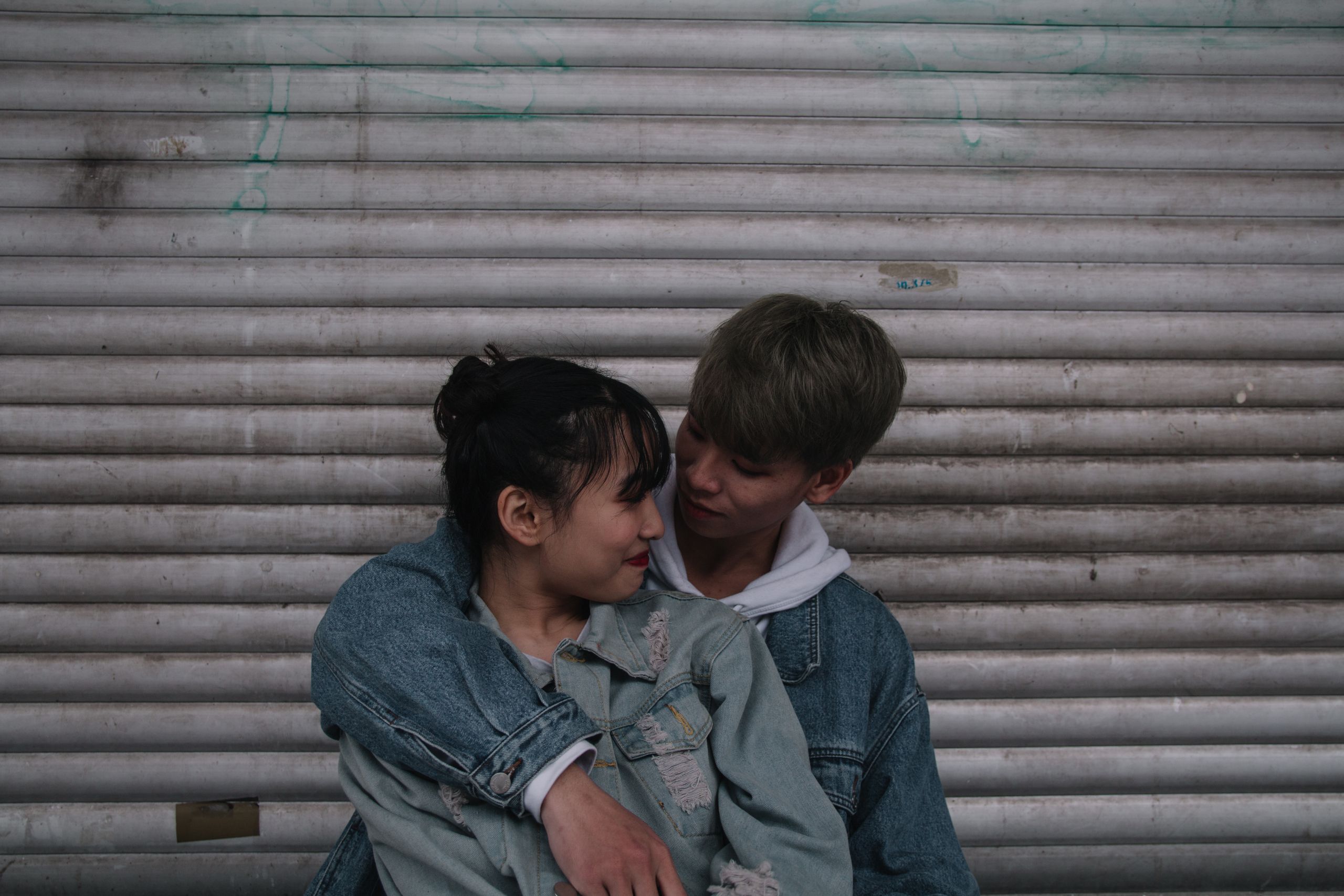 An intimate moment of a young Asian couple in love against an urban backdrop.