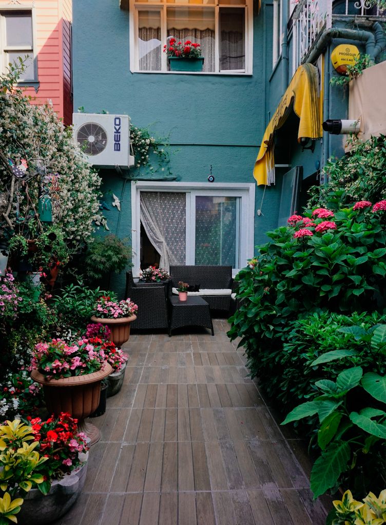 Charming urban garden patio with flower pots and seating, perfect for relaxation.
