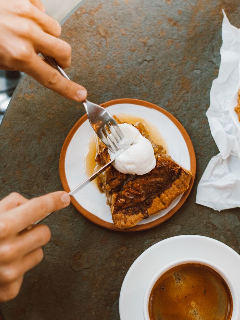Close-up of a pecan pie slice being served with cream, perfect dessert image.