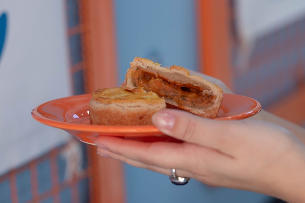Close-up of a savory pie with sauce filling held on an orange plate.