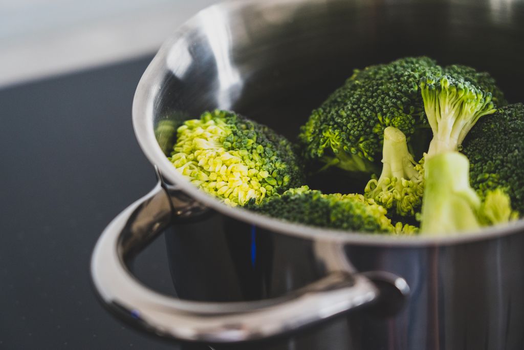 Close-up of fresh broccoli being cooked in a stainless steel pot, showcasing healthy eating.