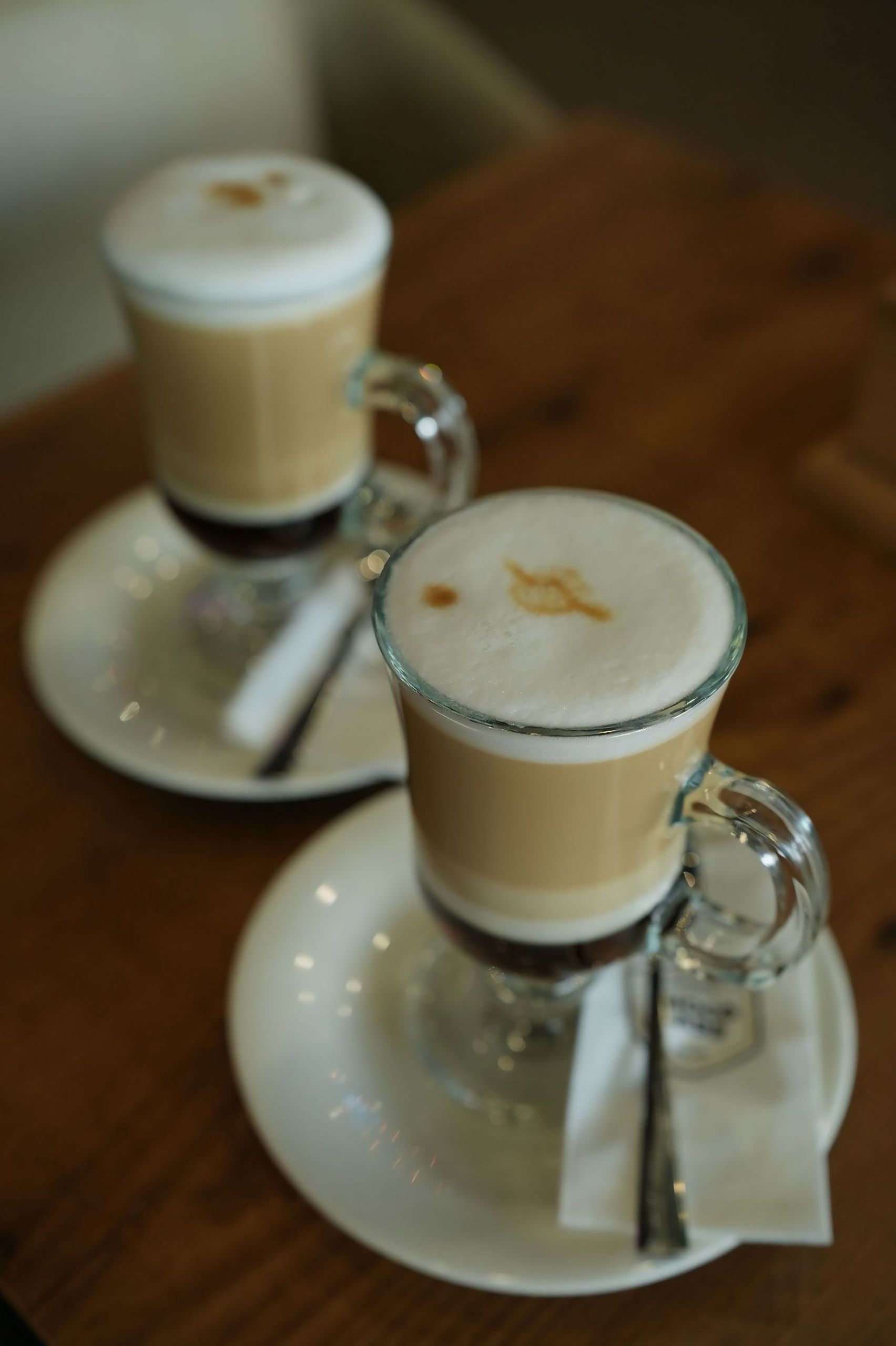 Close-up of two frothy lattes on a wooden table, perfect for a cozy coffee break.